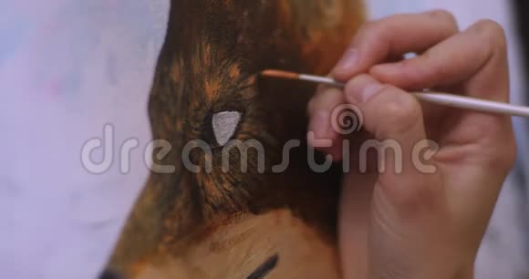 艺术家在她的车间里用丙烯酸颜料在画布上画画女孩艺术家画一只狐狸图片特写视频的预览图