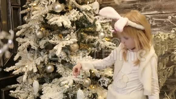 穿着兔子白色服装的小女孩装饰圣诞树视频的预览图