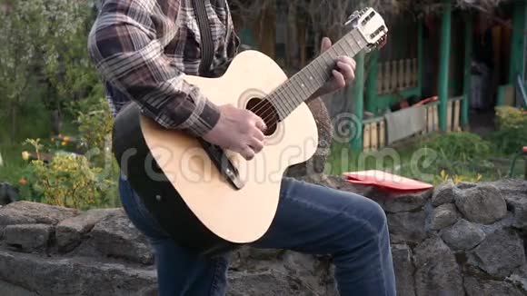 一个穿着衬衫和牛仔裤弹吉他的男人视频的预览图