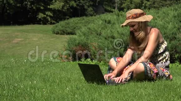 女人拥抱笔记本电脑在阳光明媚的夏日女性在公园草坪上调情4K视频的预览图