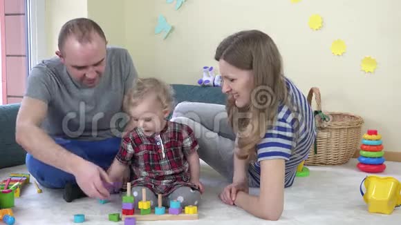 幸福的家庭爸爸妈妈和女儿一起玩把五颜六色的砖拉在柱子上视频的预览图