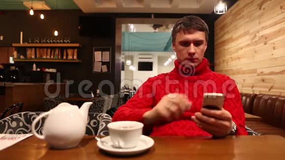 年轻人在咖啡馆里用智能手机喝茶视频的预览图
