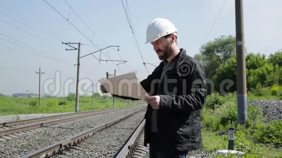 铁路交通检查员在对讲机上交谈戴着蓝图计划的白盔铁路工人视频的预览图