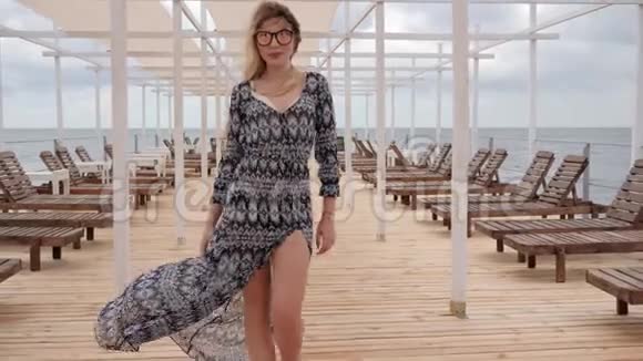 戴墨镜的女性走在海边的码头上长发女孩穿着海滨的衣服年轻的女性视频的预览图