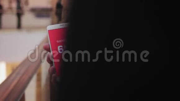 男性手握智能手机屏幕上的折扣白色文本红色背景购物中心视频的预览图