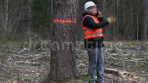 愤怒的森林督察在清林最后一棵树附近的智能手机上讲话视频的预览图