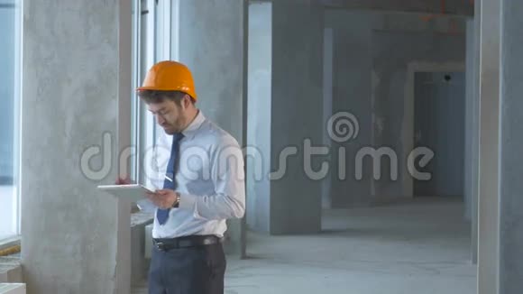 房地产经纪人建筑工程师商人在一栋新建筑内使用平板电脑检查施工现场视频的预览图