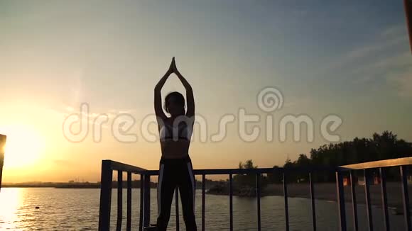 漂亮的年轻女子穿着运动服在户外练习瑜伽20岁的女孩黎明时分在海滩上做呼吸练习视频的预览图