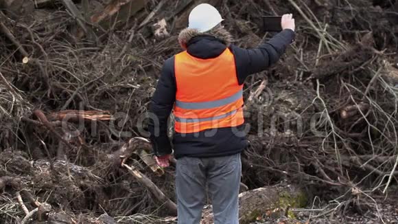 森林检查员在一堆锯成的灌木丛和菌株附近拍摄视频的预览图