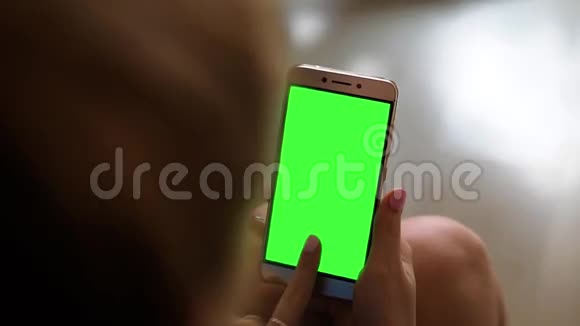 金发少女手持智能手机绿色屏幕在白天的肖像模式视频的预览图