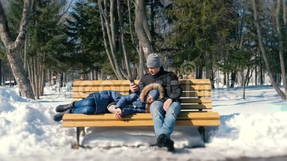 男人和女人一起在冬季城市公园的长凳上休息视频的预览图