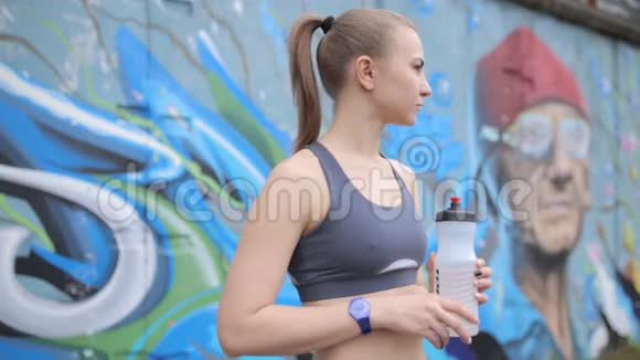 一个年轻的运动女孩在接受过体重训练后手握蛋白质视频的预览图