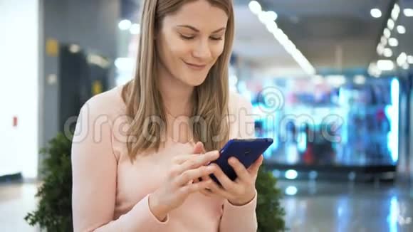 商场里有智能手机的漂亮女人浏览互联网和她的朋友交流视频的预览图