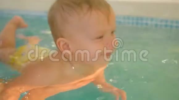 一位年轻的母亲带着一个小男孩游泳在游泳池里玩得很开心快乐的小男孩和他一起在游泳池里游泳视频的预览图