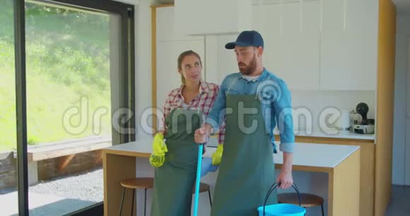 一对疲惫的夫妇在厨房休息时站在一个穿制服的职业清洁工的画像视频的预览图