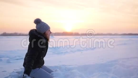 女孩把雪洒在自己身上在日落的冬季公园里尽情享受视频的预览图