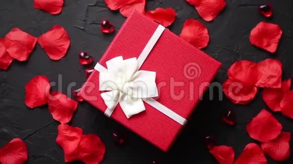 黑石桌上的礼盒带有玫瑰花瓣的浪漫节日背景视频的预览图