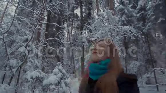 女孩在冬天的森林里散步她环顾四周欣赏周围的景色视频的预览图