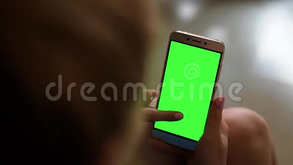 金发少女手持智能手机绿色屏幕在白天的肖像模式视频的预览图