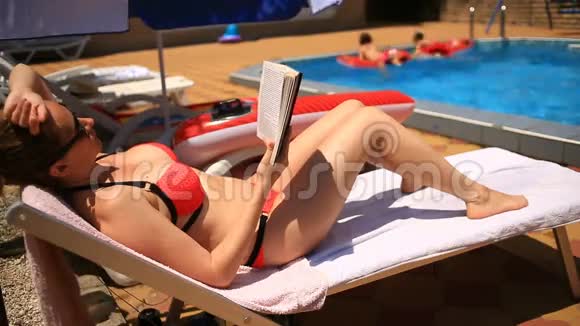 年轻优雅的女人在泳池边晒太阳视频的预览图