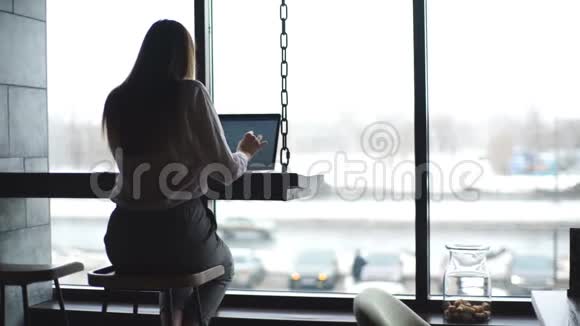 一位穿着白色衬衫带着笔记本电脑在咖啡馆工作的自信迷人的女人视频的预览图