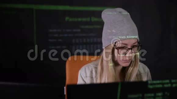 女性黑客在黑暗中在电脑里工作她脸上的二进制代码投影打滑头前景视频的预览图