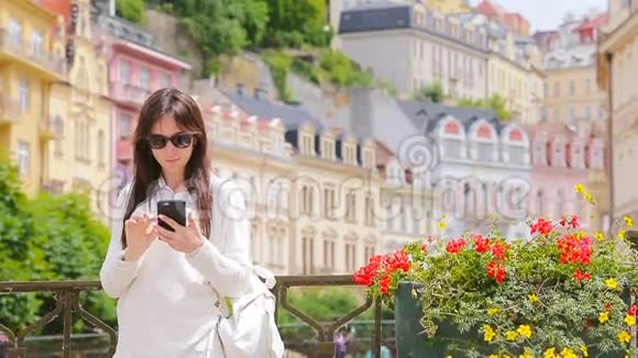 年轻女子在欧洲城市的漂亮房子周围拍摄自我肖像白人游客喜欢她的欧洲夏季视频的预览图
