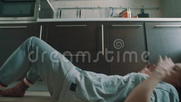 年轻的黑发女人躺在小猫地板上坐起来抓住掉下来的玻璃视频的预览图
