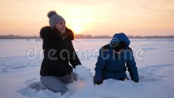 女孩和孩子把雪洒在自己身上在日落的冬季公园里尽情享受视频的预览图