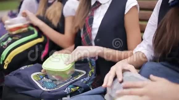 大学生在公园的长凳上吃三明治笑着说话快乐的年轻朋友一起吃饭视频的预览图
