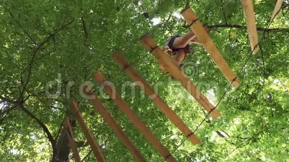一个人走在一个绳索公园的悬索小路上视频的预览图