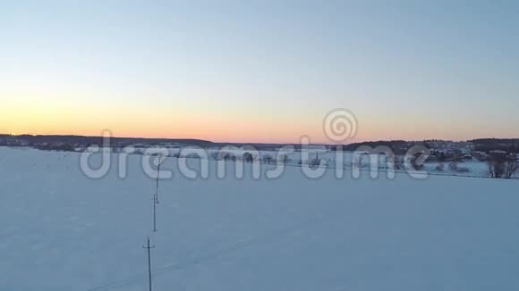 冬季日落时小型电线塔和远处房屋的空中录像视频的预览图