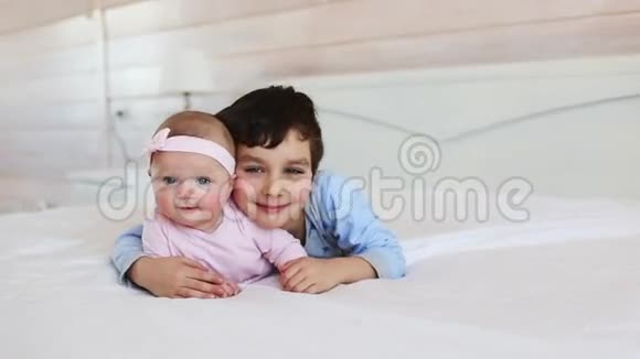 一幅可爱的弟弟和妹妹在家的床上的画像视频的预览图