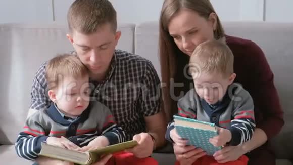 一家人的和两个双胞胎兄弟坐在沙发上看书家庭阅读时间视频的预览图