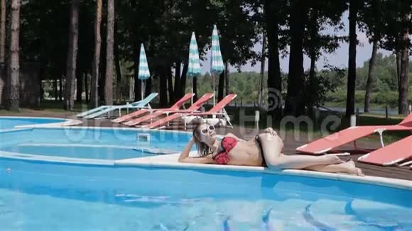 一个女人躺在泳池边的长镜头视频的预览图