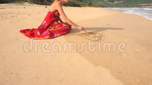 穿红衣服的女人在潮湿的沙滩上画心视频的预览图