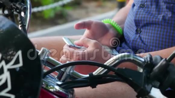 坐在复古摩托车上的男人在公园里用电话时髦的概念手的特写3840x2160视频的预览图