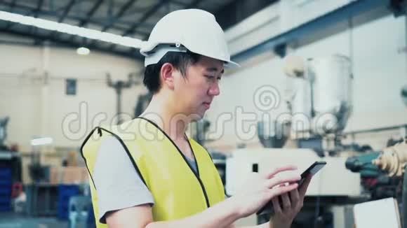 年轻的亚洲男性工厂工人使用数字平板电脑视频的预览图