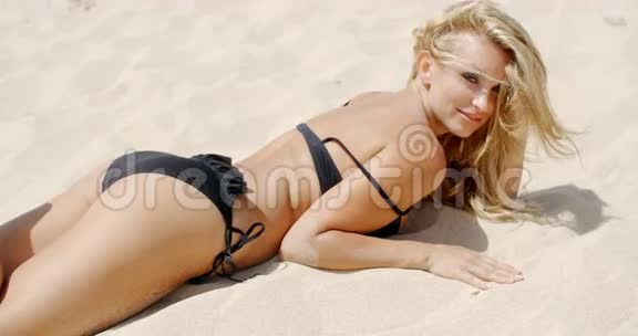 比基尼可爱的女孩躺在沙滩上视频的预览图