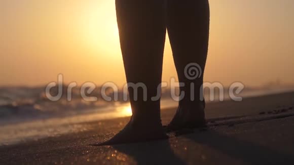 女人在日落时赤脚走在海滩上波浪在缓慢的运动中溅出镜头耀斑效应1920x1080视频的预览图