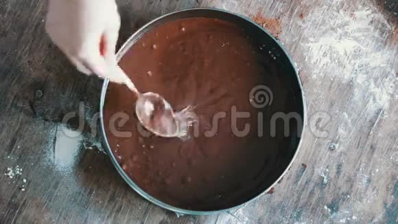 一位女士将一块巧克力面团倒入烤盘中并用高速视频将其抚平视频的预览图