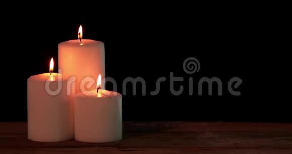 三支白色圣诞蜡烛在桌子上燃烧视频的预览图