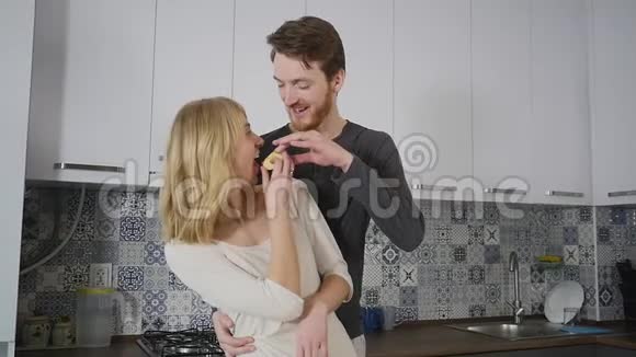 快乐的一对夫妇在厨房做饭而男人在家里吻她的女朋友视频的预览图