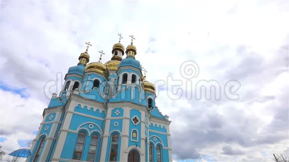 东正教寺庙寺庙上方的云彩金色的圆顶时间流逝外观从下面看蓝色的寺庙蓝色的教堂视频的预览图