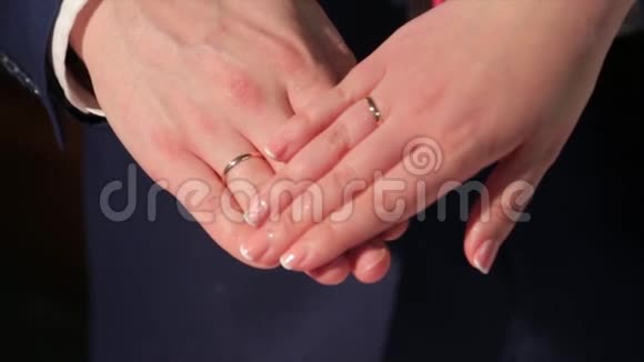 新婚夫妇手里拿着结婚戒指新娘和新郎带着结婚戒指结婚花束上的手和戒指视频的预览图