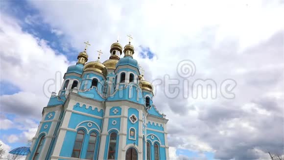 东正教寺庙寺庙上方的云彩金色的圆顶时间流逝外观从下面看蓝色的寺庙蓝色的教堂视频的预览图