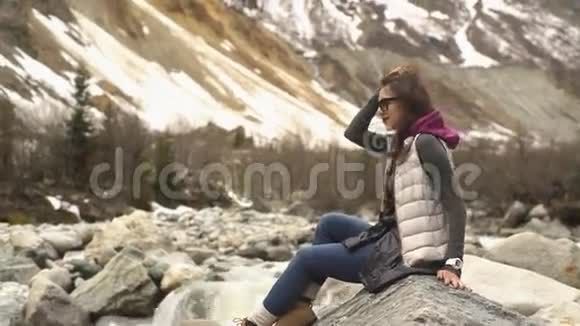 一位年轻女子坐在群山的背景上视频的预览图