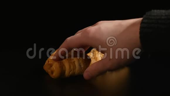 手拿牛角面包在黑色背景视频的预览图