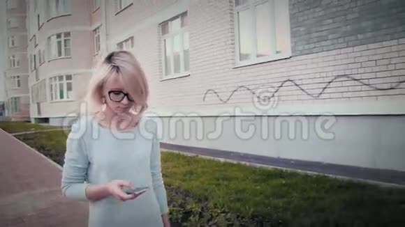 一位年轻女性使用智能手机短信和应用程序在城市中行走的侧视图视频的预览图