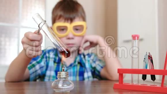 家庭化学实验男孩在燃烧的酒精灯上用红色液体加热试管液体沸腾了视频的预览图